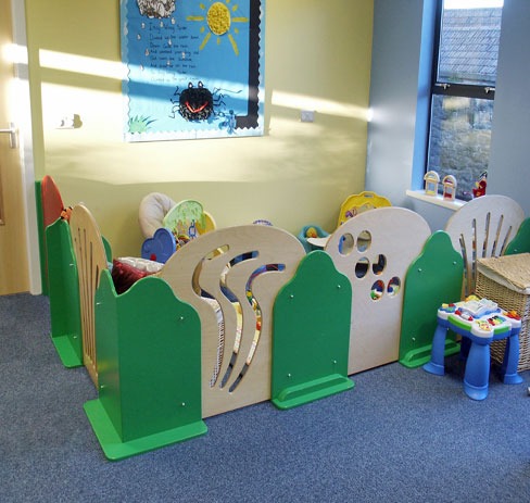 Shaped play area screens in birch ply and green panels in a nursery