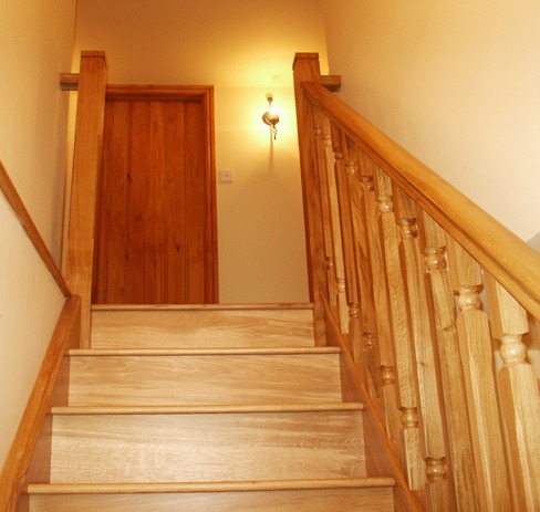 Straight oak staircase with turned spindles leading to a panelled door