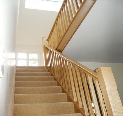 Carpeted staircase with an oak handrail and spindles