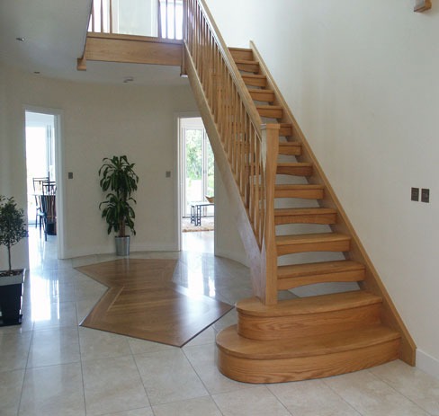 Open oak staircase rising through a bright entrance hall